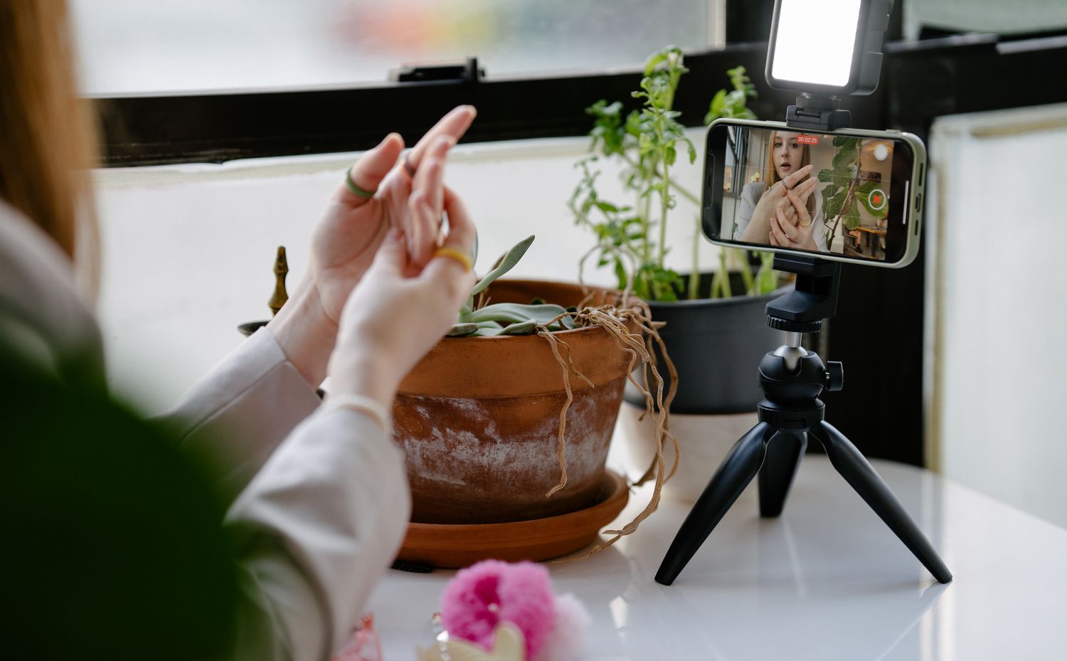 A smartphone on a tripod filming a content creator at a table