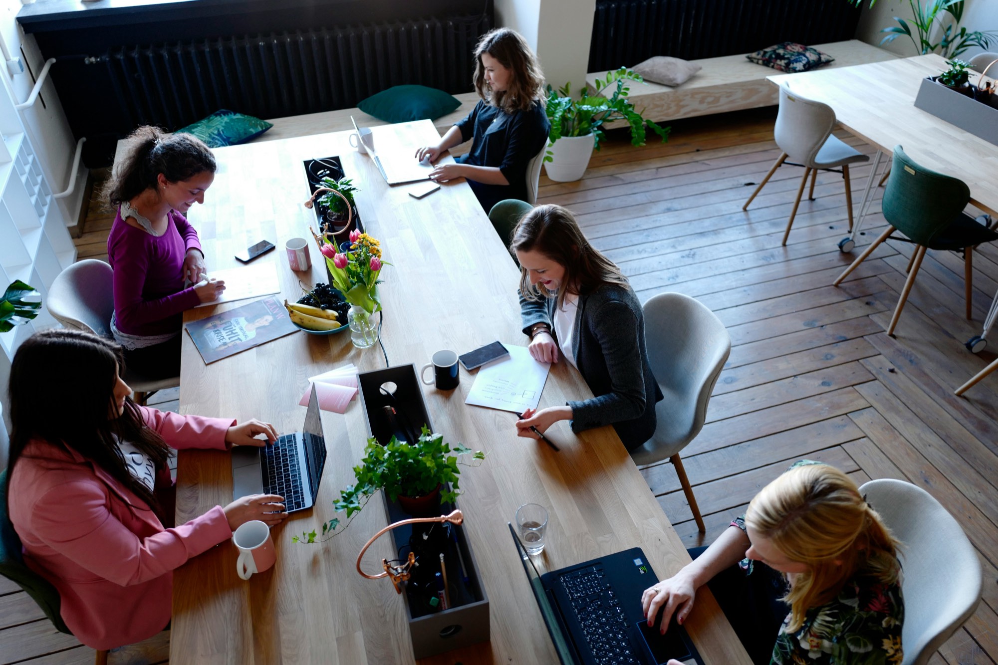 People working on laptops at a shared table in a coworking space